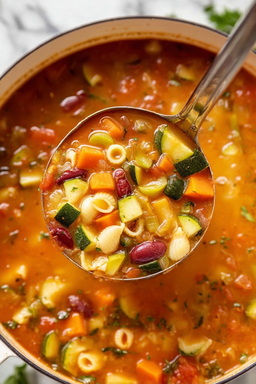 A close-up view of a pot filled with vegetable soup showing a rich, orange broth with visible layers of diced orange carrots, green zucchini pieces, chopped celery, red kidney beans, small shell pasta, and bits of green herbs. A ladle lifts a portion of the soup, displaying the chunky vegetables and pasta clearly. The pot is white, and the background has a white marbled texture. photo taken with an iphone --ar 2:3 --v 7